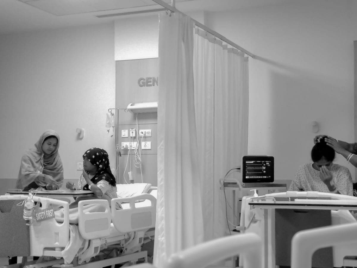 Women sitting with patients in a hospital ward in Kolkata